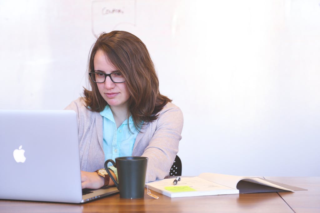 Smiling Woman Looking Using Macbook Sitting Near Table