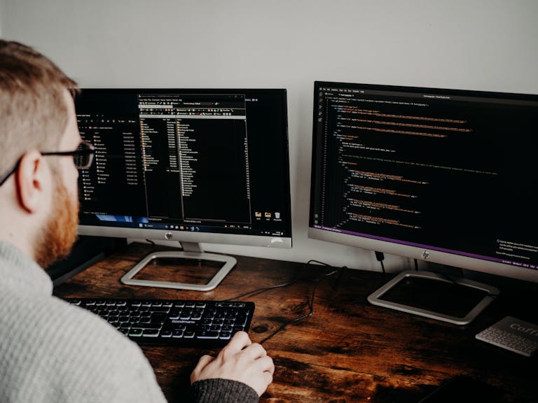 Man Coding on Computers Sitting at Desk